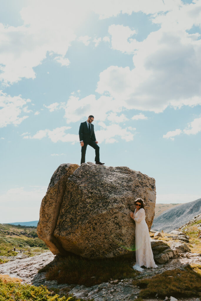 groom standing on rock looking down at bride 
